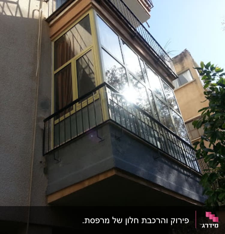 A balcony with aluminum and glass panels reflecting sunlight.